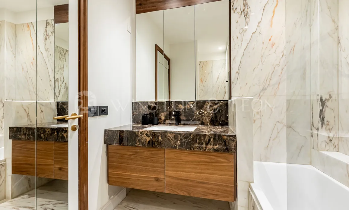 Salle de bain de luxe moderne. Marbre veiné clair et foncé, meuble vasque en bois élégant et grand miroir. Design intérieur haut de gamme.