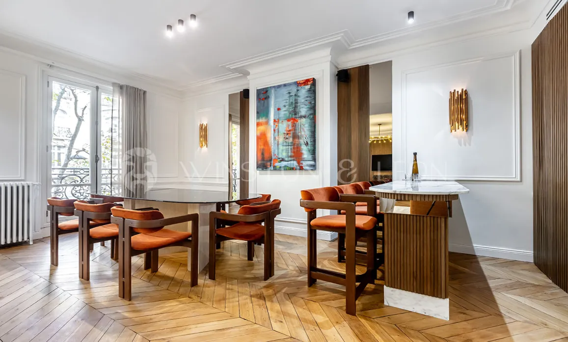 Appartement de luxe : salle à manger et bar design, parquet chevrons, art moderne. Espace élégant et lumineux pour recevoir.