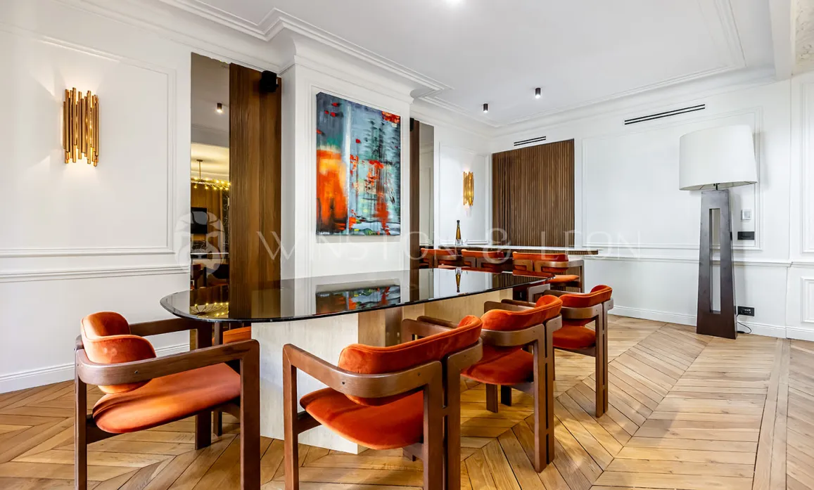 Intérieur de luxe moderne: salle à manger élégante avec table en verre, chaises orange velours, art contemporain et parquet. Design raffiné.