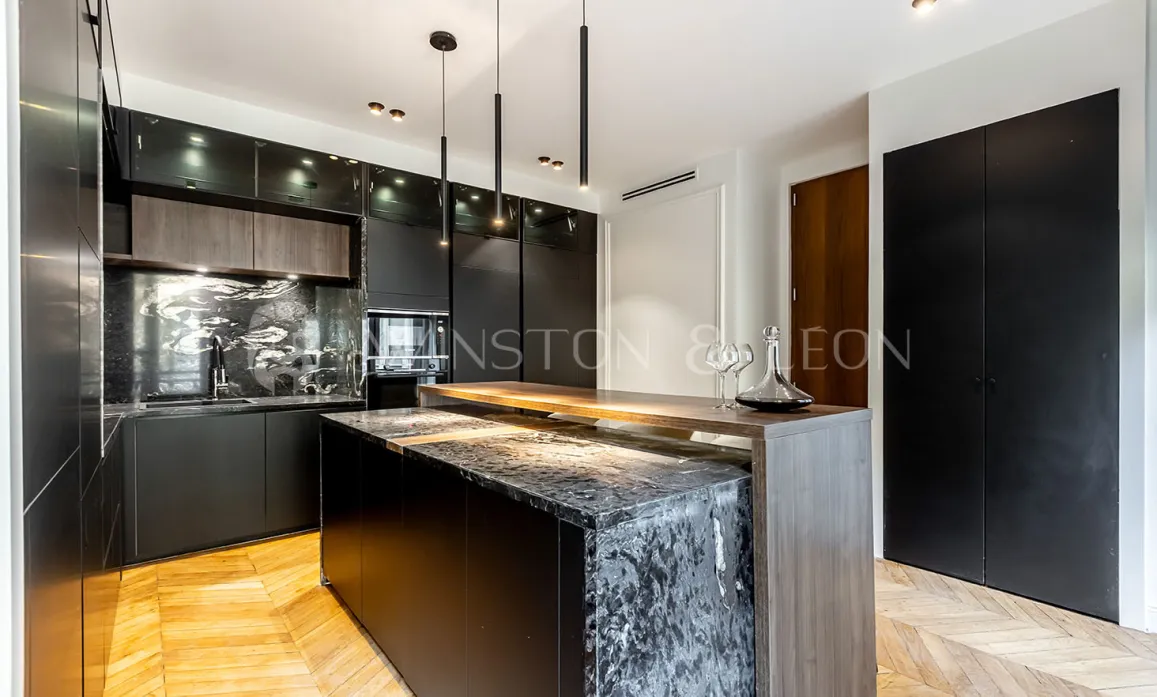 Cuisine de luxe contemporaine noire, îlot marbre, bois, parquet. Design élégant et sophistiqué pour un intérieur haut de gamme.