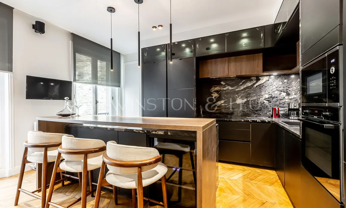 Cuisine luxe moderne avec îlot bois, marbre noir veiné, tabourets design et luminaires suspendus.