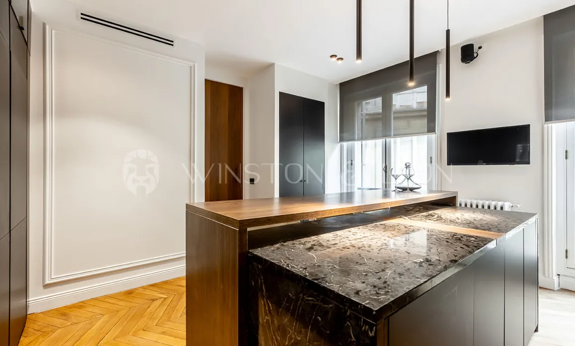 Intérieur luxe moderne: cuisine design avec îlot central marbre et bois, éclairage suspendu, TV murale. Élégance contemporaine.
