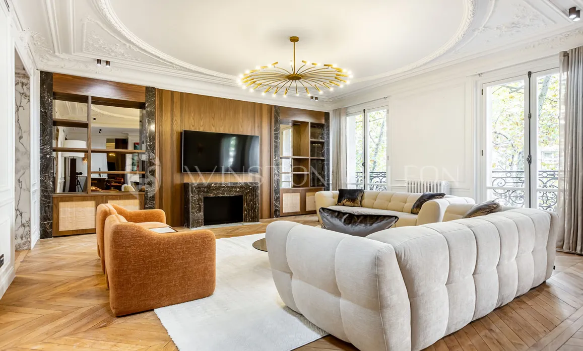 Superbe salon de luxe: design moderne, cheminée marbre, parquet, moulures, canapés design. Ambiance lumineuse et raffinée pour appartement parisien.