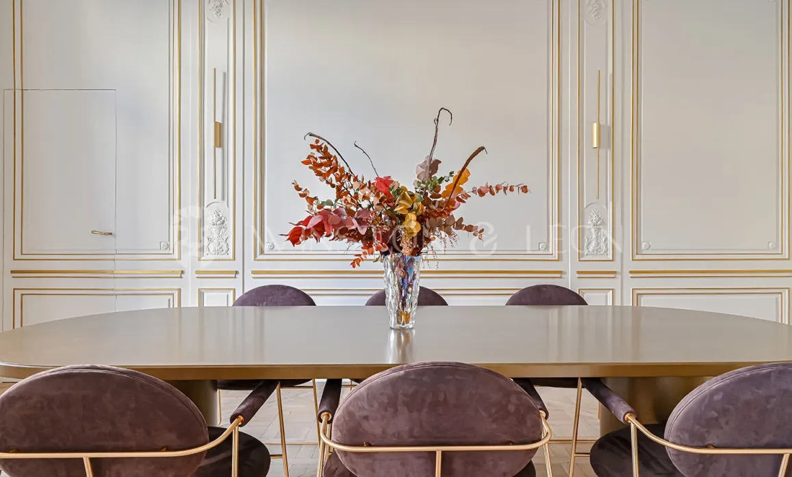 Appartement haussmannien de luxe: salle à manger élégante. Moulures dorées, mobilier contemporain velours et table design. Décoration raffinée.