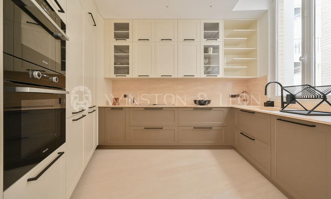 Cuisine de luxe moderne bicolore (crème/taupe), électroménager Miele intégré. Design élégant et fonctionnel pour un intérieur haut de gamme.