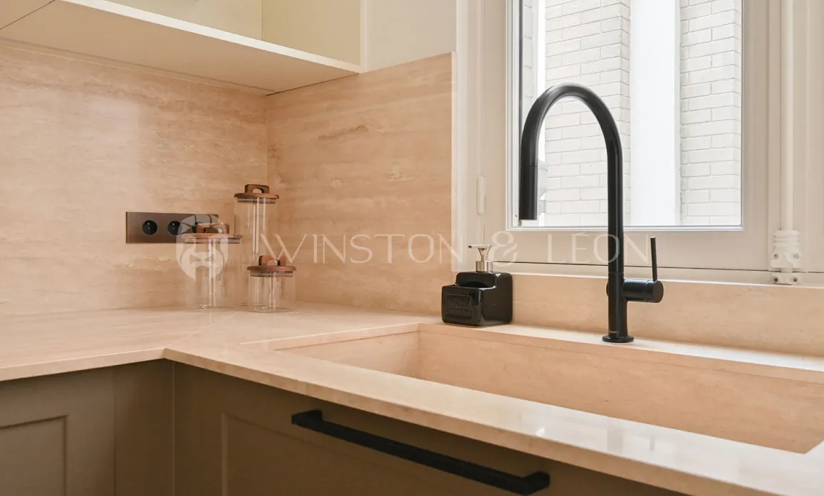Cuisine luxe: évier intégré pierre naturelle, robinet noir mat, plan de travail élégant. Ambiance moderne et épurée.