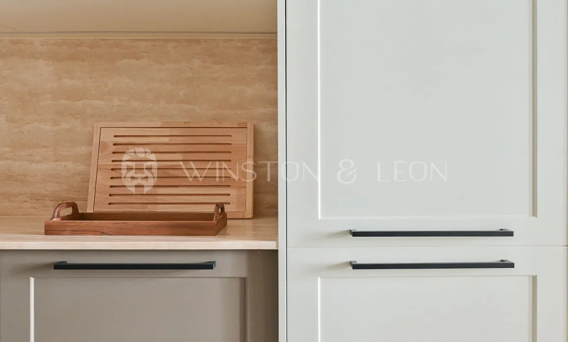 Cuisine de luxe moderne: armoires claires, poignées noires, crédence travertin, accents bois. Design élégant et fonctionnel.