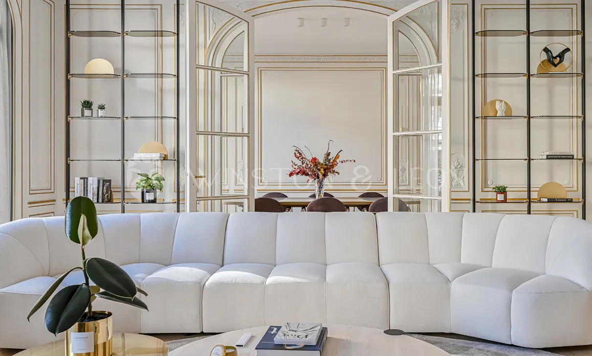 Élégant salon de luxe, canapé blanc moderne, moulures dorées. Ambiance chic et raffinée pour un appartement haussmannien d'exception.