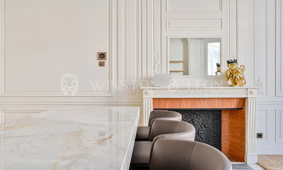 Intérieur luxe parisien: table marbre, cheminée classique, moulures. Élégance intemporelle pour propriété haut de gamme.