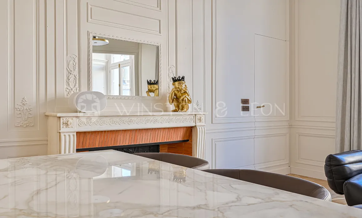 Élégant intérieur Haussmannien: boiseries, cheminée ornée, miroir, table marbre. Luxe parisien raffiné, design chic.
