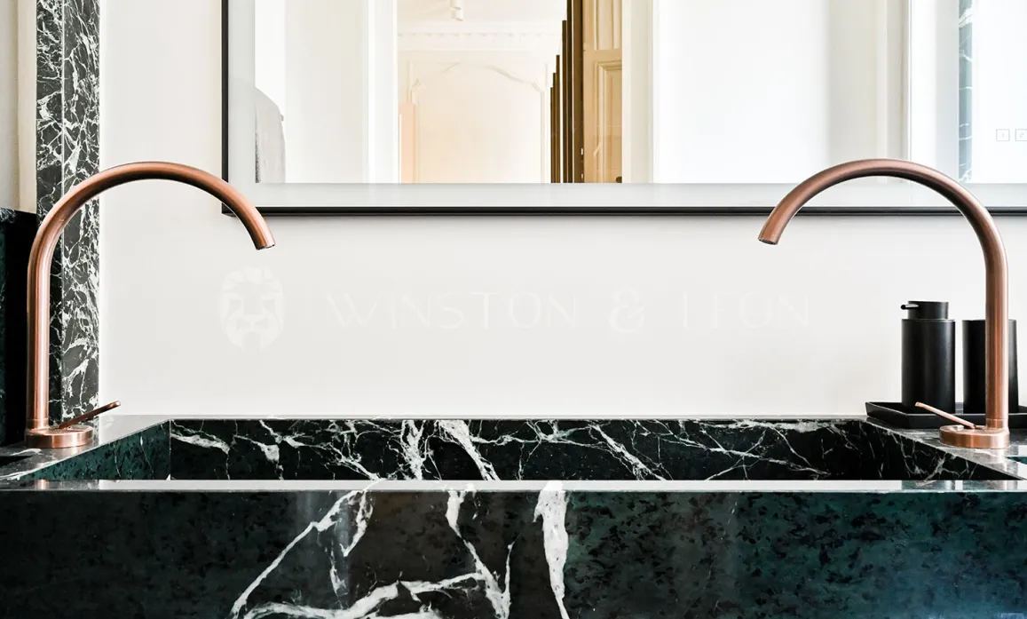 Salle de bain de luxe: double vasque en marbre vert, robinetterie cuivre design. Élégance moderne pour un intérieur raffiné.