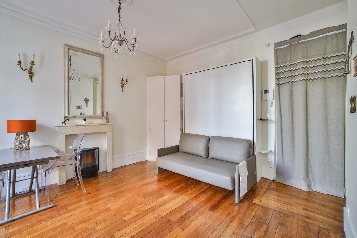 Studio parisien élégant et lumineux. Parquet, cheminée, lit escamotable design. Optimisation d'espace luxe. Idéal investissement.