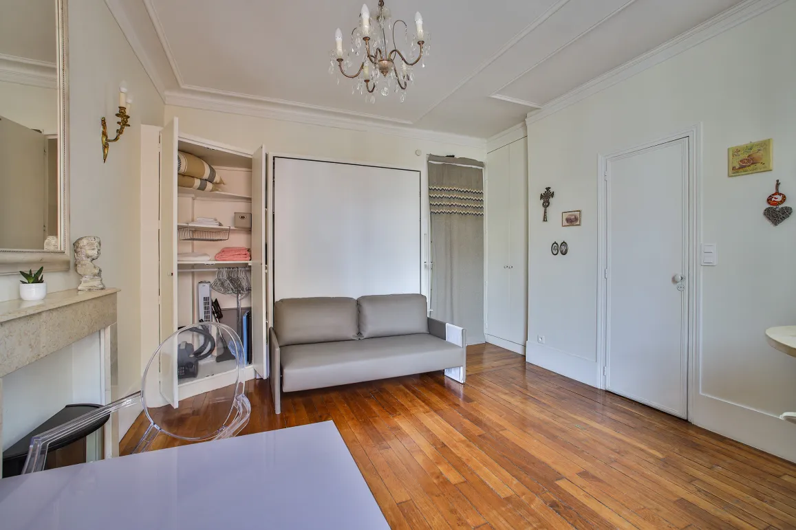 Studio de luxe optimisé avec canapé convertible, parquet, moulures et rangements intégrés. Élégance et fonctionnalité à Paris.
