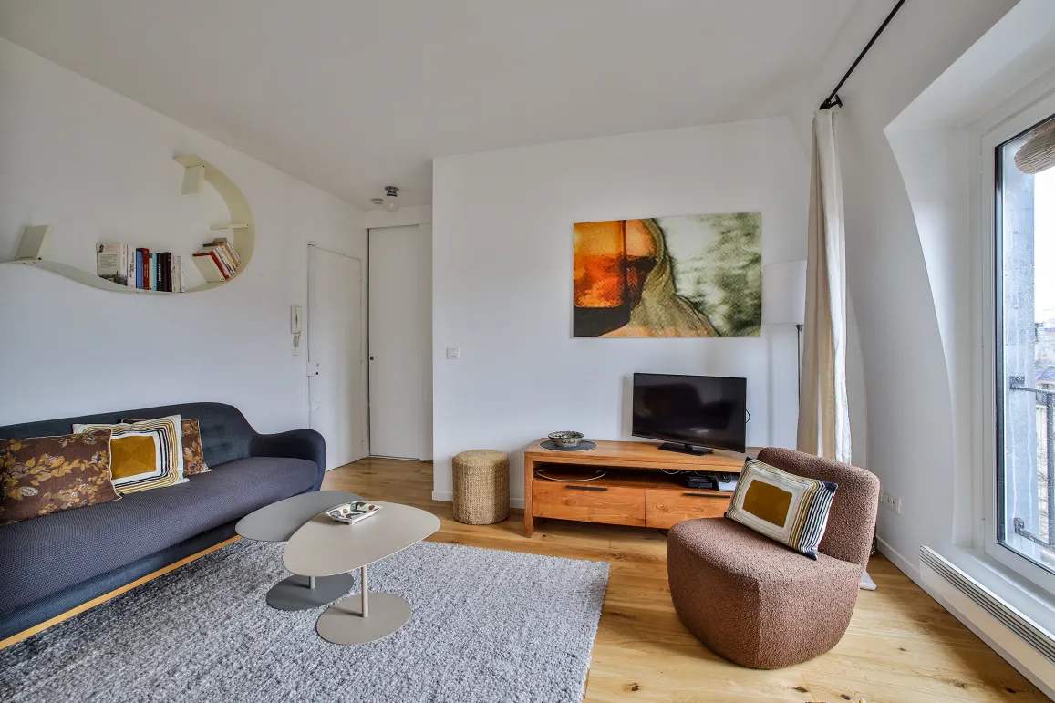 Salon moderne et lumineux avec mobilier design, art contemporain et parquet. Ambiance raffinée pour un appartement de luxe parisien.