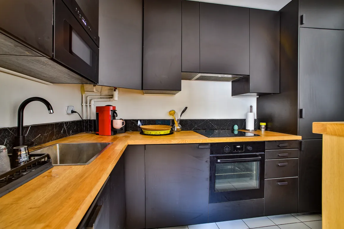 Cuisine design luxe: meubles noirs mats, plan de travail bois clair, équipée. Élégance contemporaine.