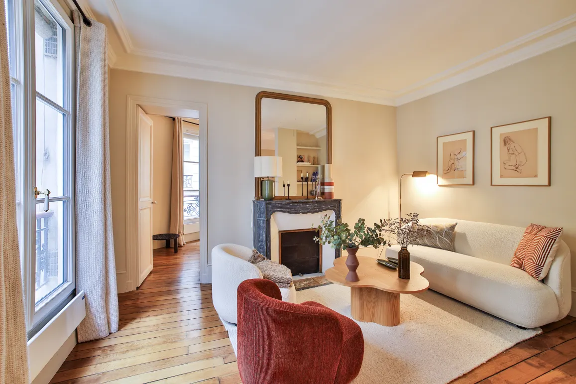 Salon parisien luxe, design moderne et élégant avec cheminée, parquet et lumière naturelle. Idéal pour un appartement haut de gamme.