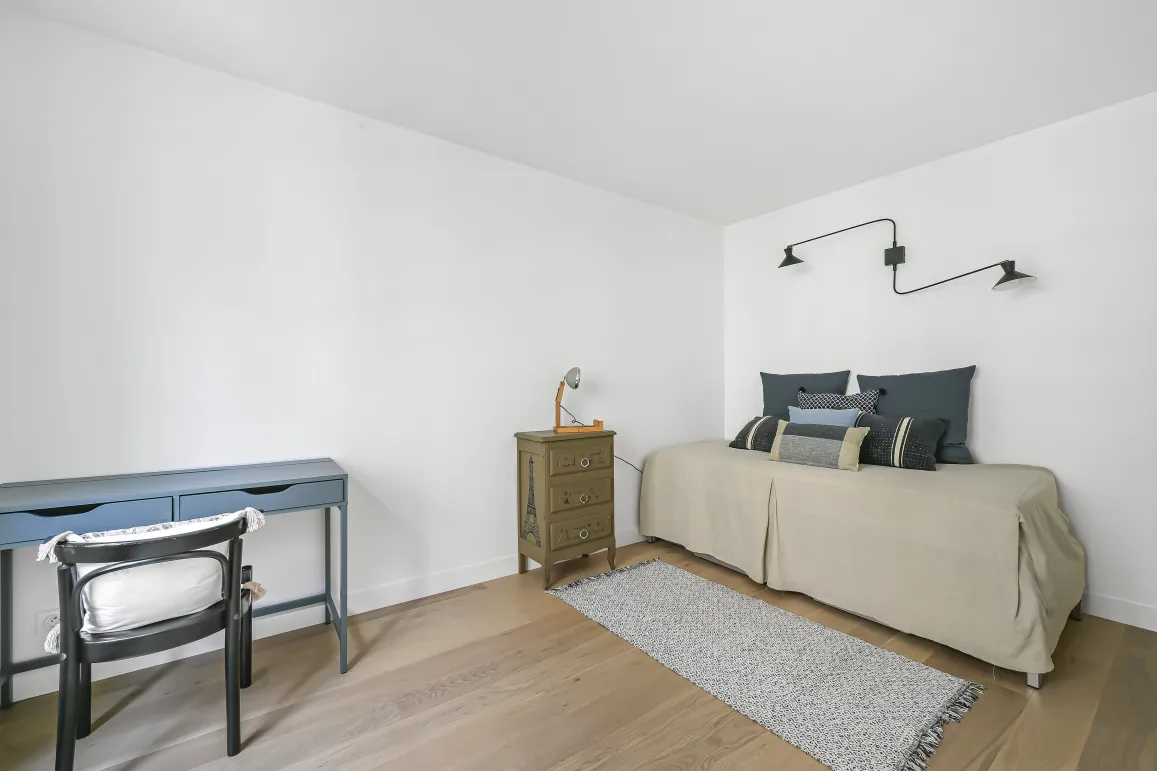 Chambre/bureau minimaliste et lumineux. Parquet clair, lit design, bureau élégant. Espace polyvalent raffiné pour propriété de luxe.