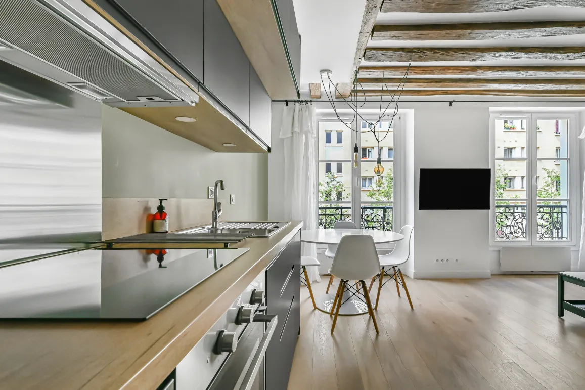 Appartement de luxe: cuisine moderne ouverte sur séjour lumineux, poutres apparentes, parquet. Élégance parisienne.