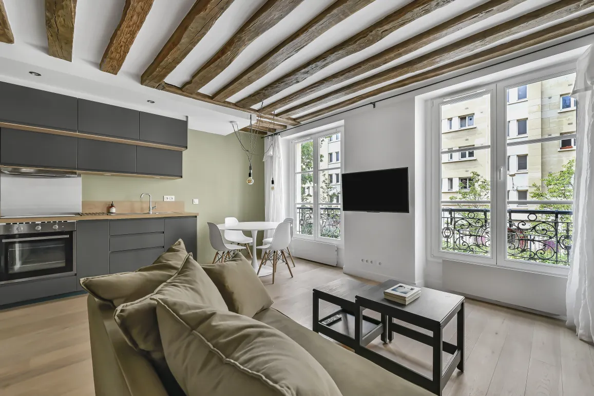 Appartement de luxe rénové, salon-cuisine ouvert, poutres apparentes, design moderne, lumineux. Idéal investissement Paris.