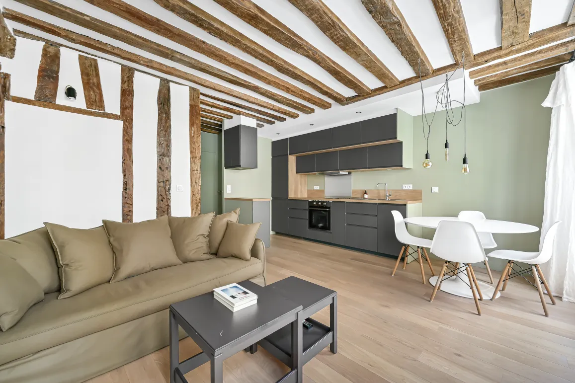 Appartement de luxe avec poutres apparentes, cuisine moderne ouverte et salon élégant. Design contemporain, parquet clair.