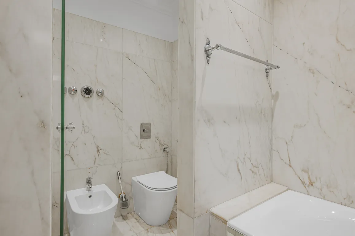 Salle de bain de luxe en marbre avec douche, baignoire, WC et bidet. Design élégant et finitions haut de gamme.