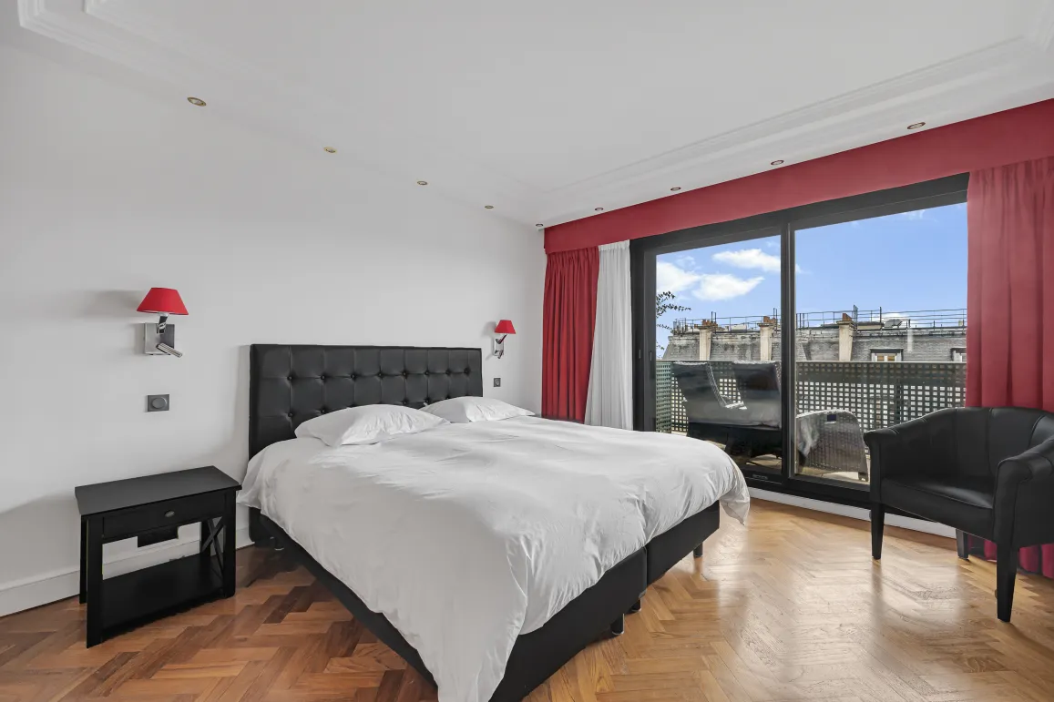 Chambre de luxe moderne avec lit king-size, parquet, balcon privé et vue ville. Design élégant et lumineux pour un confort optimal.