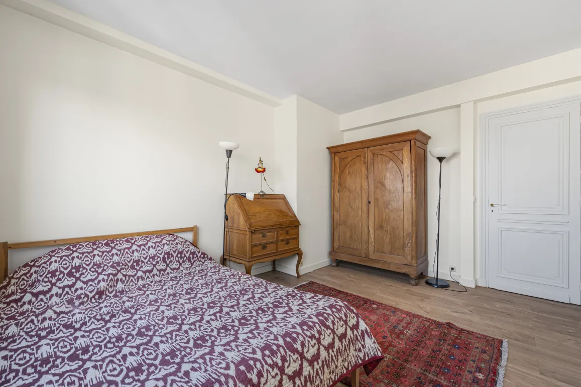 Chambre élégante avec mobilier ancien en bois massif : armoire, bureau secrétaire. Lit confortable, parquet, tapis oriental. Charme intemporel.