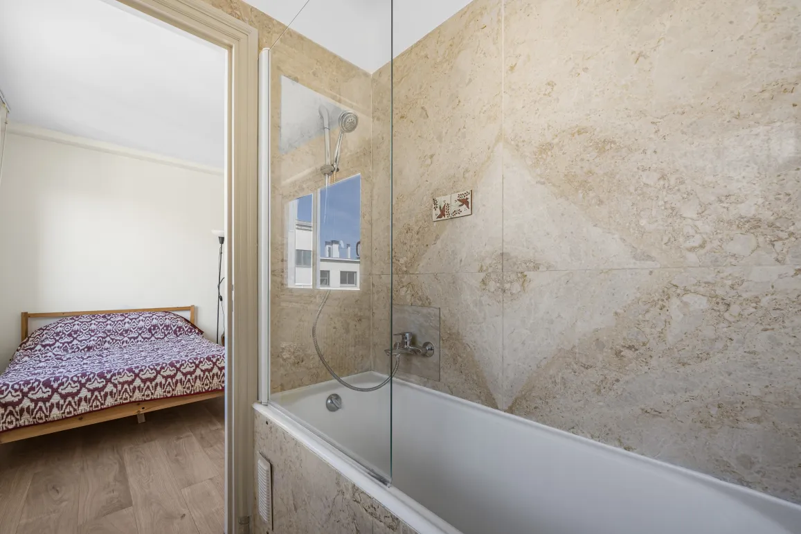Découvrez cette suite moderne: salle de bain avec baignoire, douche et murs en pierre naturelle, ouverte sur une chambre lumineuse. Luxe fonctionnel.