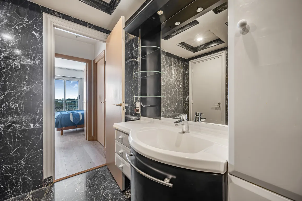 Salle de bain élégante en marbre noir, design moderne avec vasque intégrée. Accès suite parentale lumineuse avec vue. Luxe et confort.