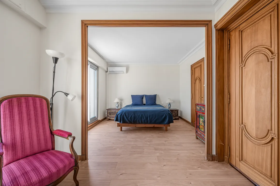 Suite parentale lumineuse et élégante avec lit double bleu, parquet bois clair et mobilier raffiné. Un intérieur de charme pour propriété de luxe.