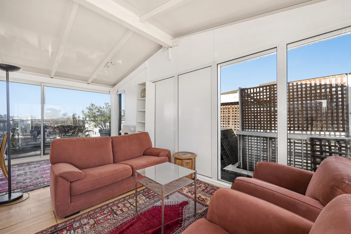 Salon lumineux penthouse avec vue terrasse, grandes baies vitrées. Appartement de luxe, espace moderne et confortable. Idéal vie urbaine.