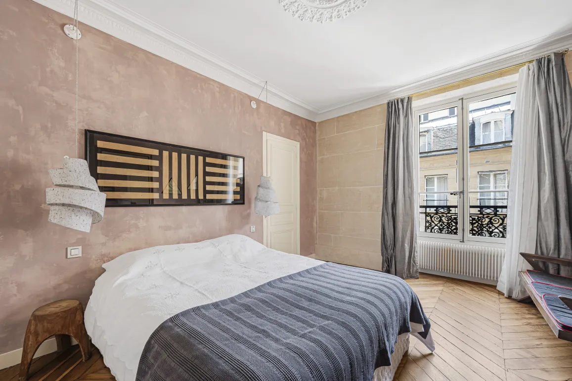 Chambre parisienne de luxe. Design moderne, murs texturés, parquet, vue ville. Ambiance élégante et raffinée.