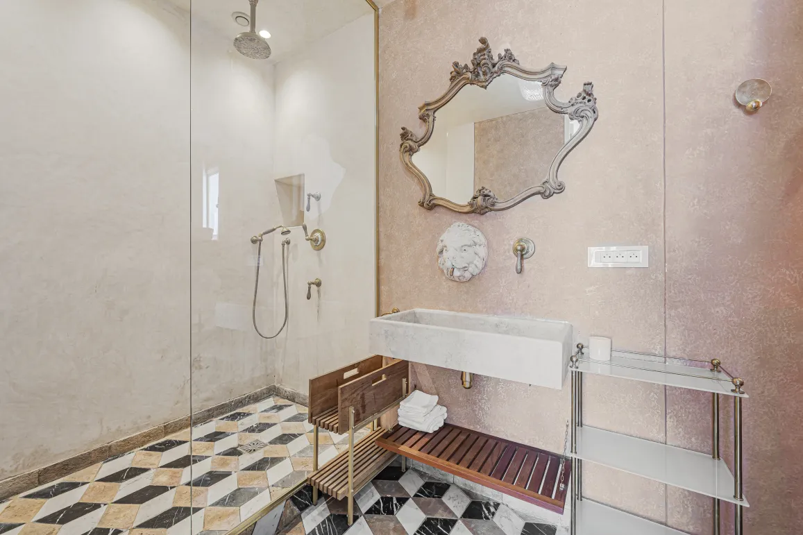 Salle de bain de luxe. Douche vitrée, miroir baroque, lavabo en pierre, sol marbre géométrique. Design élégant et raffiné.