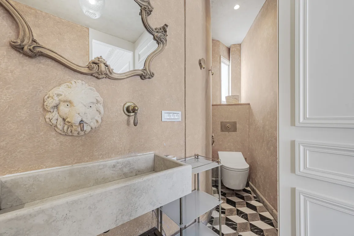Luxueuse salle d'eau: miroir baroque, lavabo pierre, robinet tête de lion. Design élégant, carrelage géométrique. Intérieur chic et raffiné.