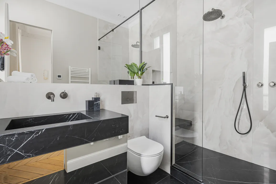 Salle de bain luxe marbre noir et blanc. Douche à l'italienne, lavabo design. Élégance contemporaine pour propriété haut de gamme.