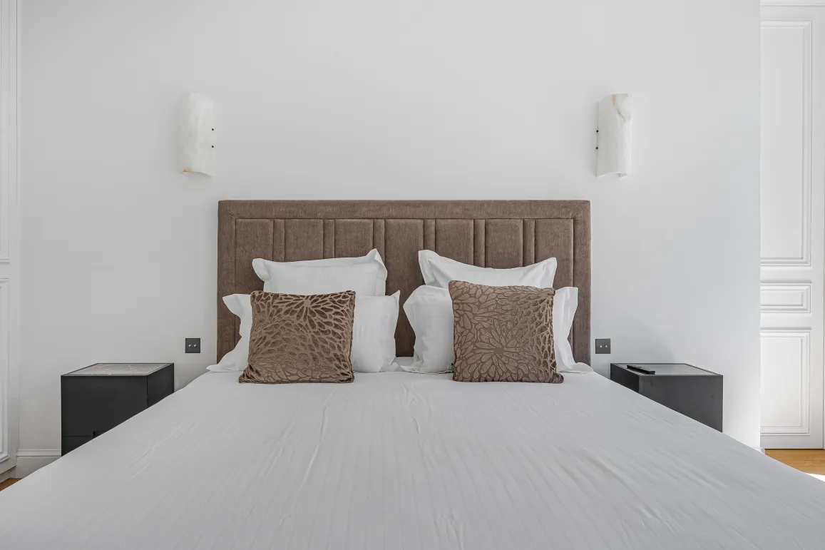 Chambre parentale de luxe, lit double confortable avec tête de lit capitonnée, décoration moderne et élégante. Idéal pour un appartement haut de gamme.