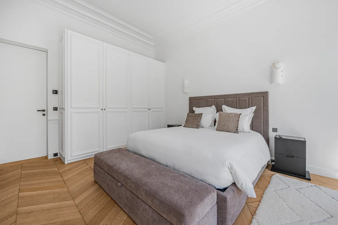 Chambre de luxe contemporaine, design épuré. Lit confortable, dressing intégré, parquet. Ambiance lumineuse et élégante.
