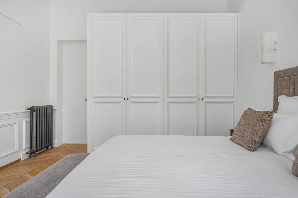 Chambre luxe épurée. Placards intégrés, lit confortable, parquet. Design contemporain, élégance et sérénité pour une suite parentale.