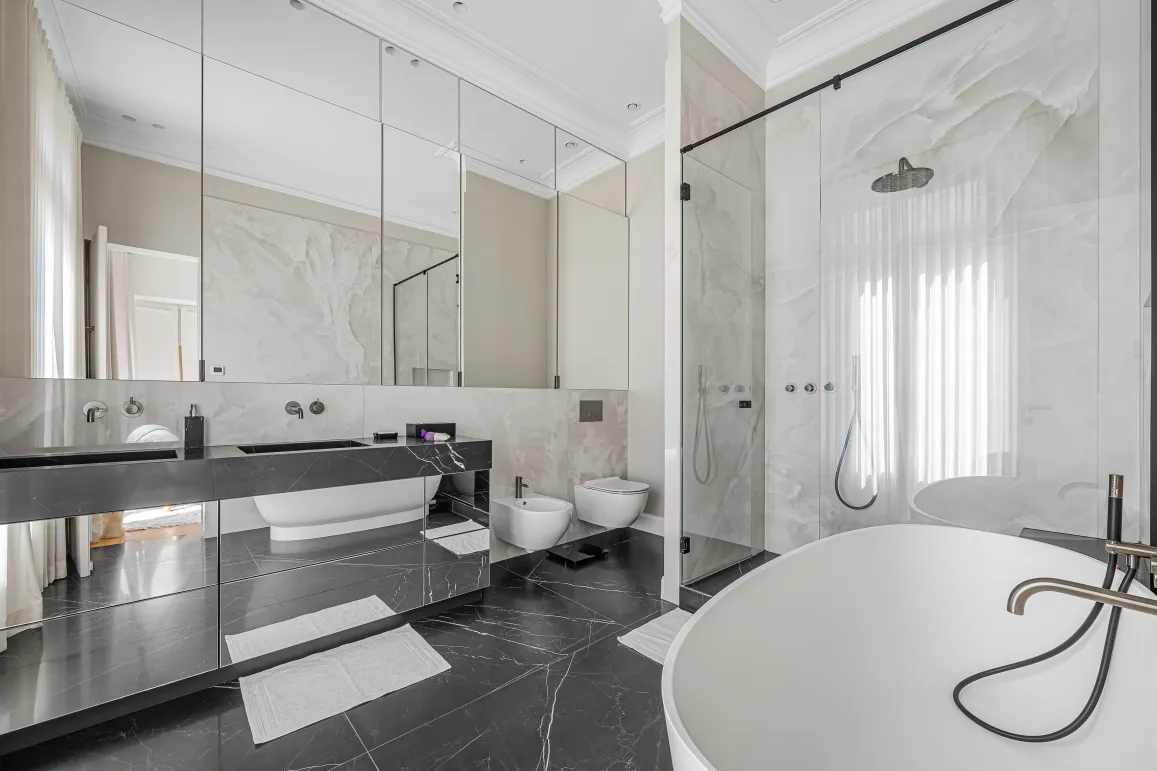 Salle de bain de luxe moderne avec marbre noir et blanc, double vasque, baignoire îlot et douche à l'italienne. Design élégant et haut de gamme.