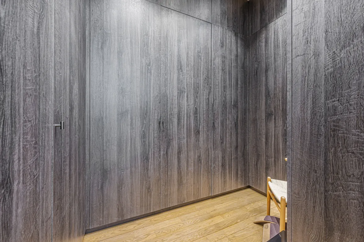 Design luxe: boiseries sombres intégrées, parquet clair. Intérieur moderne et épuré, idéal pour un couloir ou dressing haut de gamme.