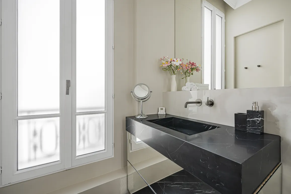 Salle de bain de luxe avec lavabo en marbre noir, design moderne et élégant. Ambiance raffinée, fenêtre lumineuse.