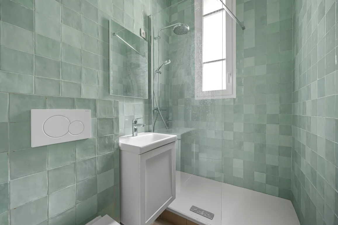 Salle de bain contemporaine avec douche à l'italienne, carrelage vert d'eau lumineux. Design épuré pour un intérieur de luxe moderne.