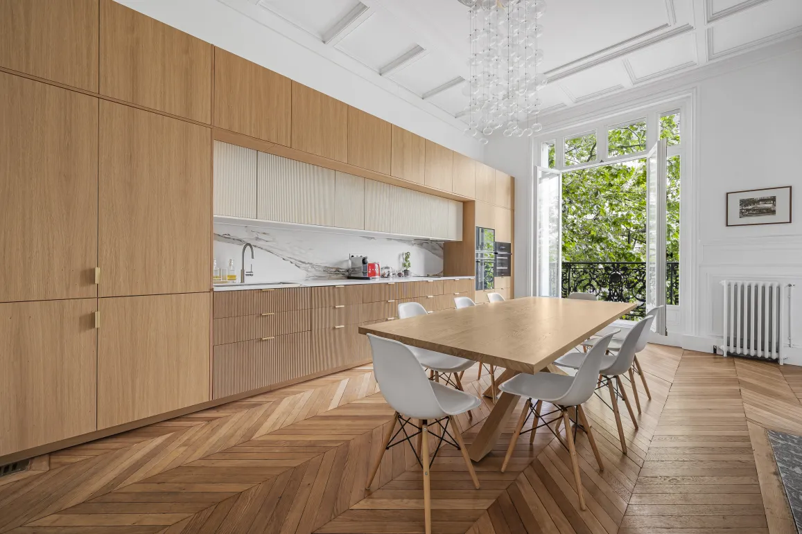 Cuisine salle à manger de luxe, design moderne et élégant. Parquet, boiseries sur mesure, marbre, vue verdoyante. Appartement parisien.