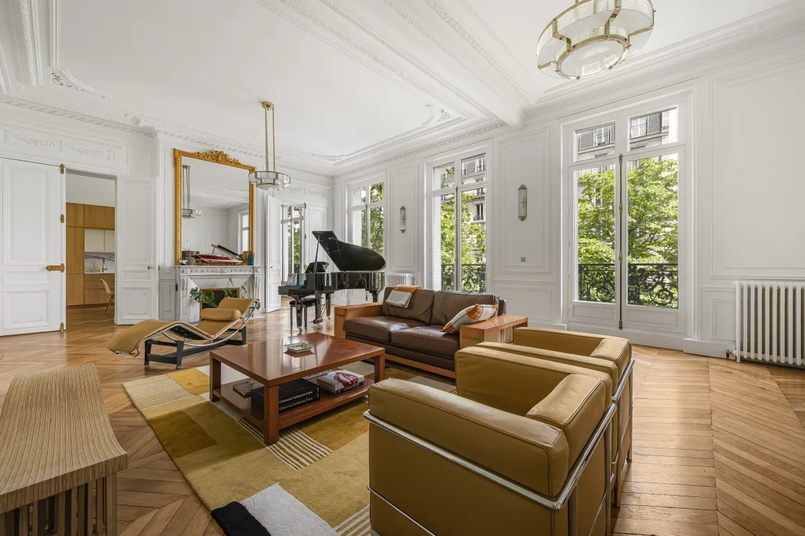 Salon Haussmannien de luxe à Paris: piano, parquet, moulures, cheminée, vue verdoyante. Élégance et lumière.