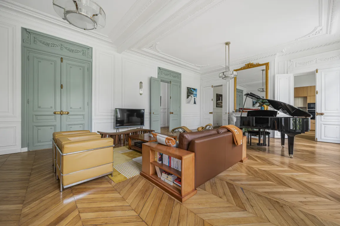 Salon de luxe parisien, parquet chevrons, moulures, piano à queue. Design élégant et raffiné pour appartement haussmannien.