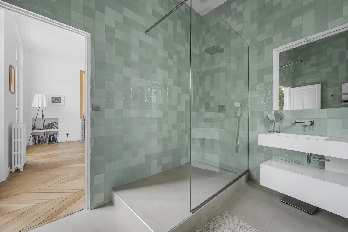 Salle de bain de luxe moderne avec douche à l'italienne et carrelage zellige vert d'eau. Design élégant pour un appartement haut de gamme.