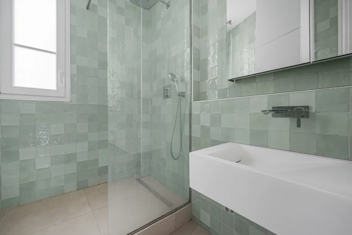 Salle de bain de luxe moderne. Douche à l'italienne, carrelage zellige vert d'eau, lavabo design. Élégance et raffinement pour un intérieur haut de gamme.