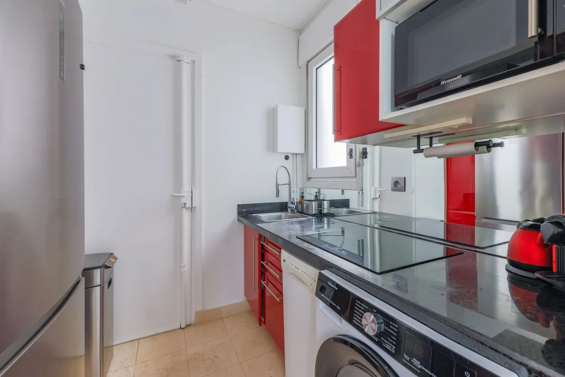 Cuisine moderne et élégante, entièrement équipée (lave-linge, micro-ondes), design contemporain rouge et noir. Idéal pour appartement de luxe.