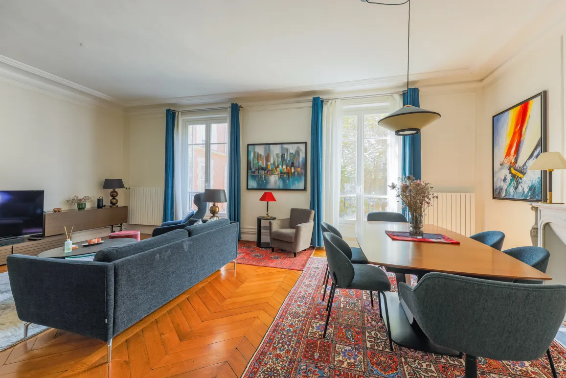 Appartement de luxe spacieux et lumineux. Salon-salle à manger élégant avec parquet, grandes fenêtres et design contemporain. Idéal pour un style de vie parisien chic.