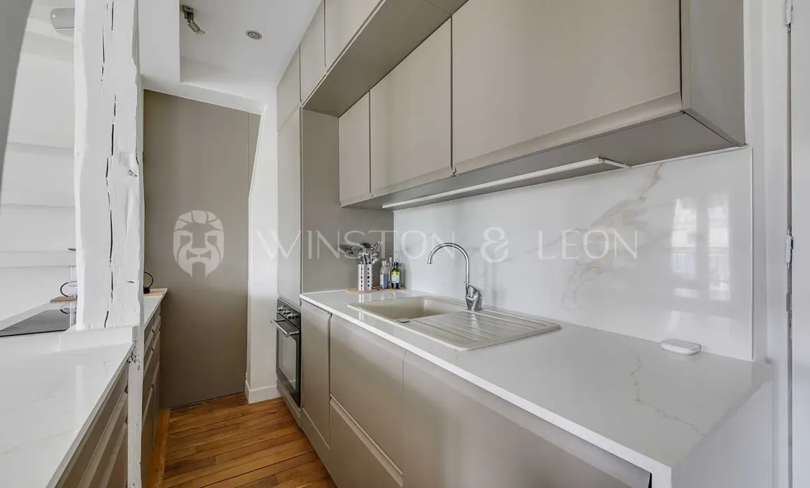 Cuisine moderne et élégante avec meubles gris clair, plan de travail et crédence en marbre. Design luxueux pour appartement parisien.